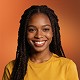Smiling woman with braided hair wearing a yellow top, portrait on orange background