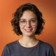 Smiling woman with glasses and dark hair, portrait on orange background